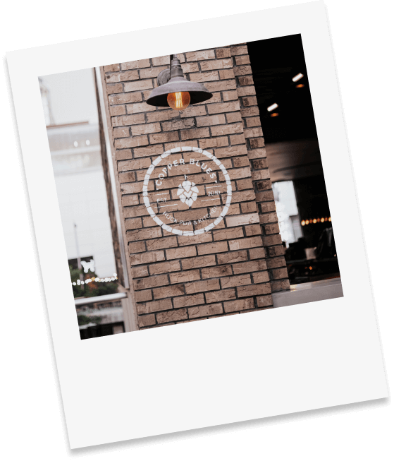 polaroid photo of the Copper Blues logo on a brick wall