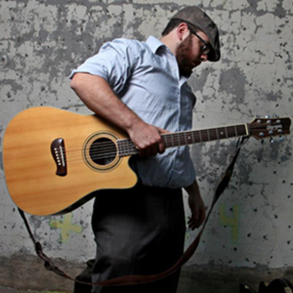 A man holding a guitar walking