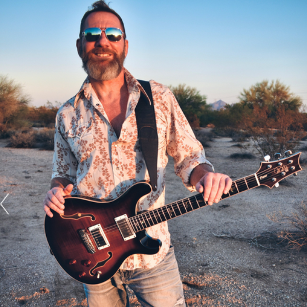 Man holding a guitar in the desert