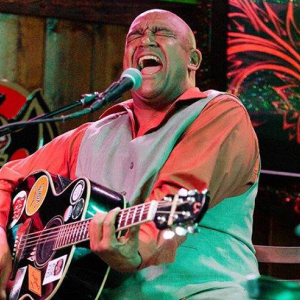 Man singing into a microphone while playing a guitar