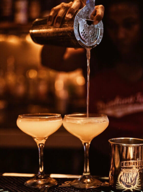 a bartender pouring two cocktails