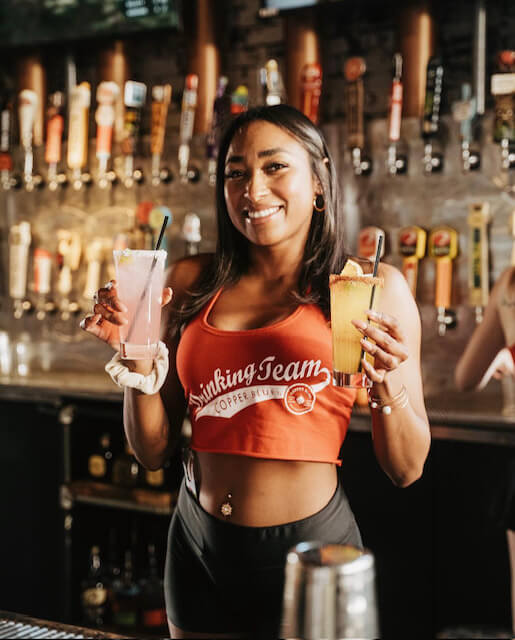 bartender holding two drinks smiling